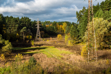 Fototapeta na wymiar High-voltage power line passing through a picturesque valley surrounded by autumn nature, electric wires suspended on high metal poles