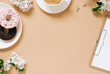 Obraz na płótnie Canvas Spring flat lay with apple flowers. Woman's workplace. Tea break with Donut. Copy space