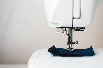 Part of a sewing machine with a needle and a thread pulled into it close-up