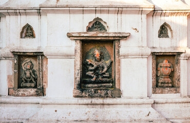 Fototapeta na wymiar Frontal view of a white temple wall with Buddhist statues.