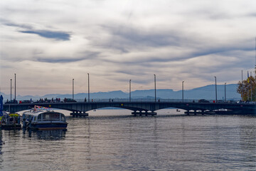 Fototapeta na wymiar Beautiful scenic view of Limmat River, Quay Bridge, Lake Zürich and Swiss Alps seen from the old town of Zürich on a blue cloudy autumn day. Photo taken October 30th, 2022, Zurich, Switzerland.
