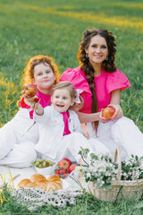 Cute mom and two daughters are having a picnic in the spring garden. Outdoor activity. Sweet moments family