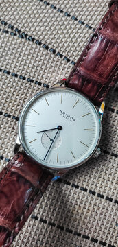 BANGKOK, THAILAND - DECEMBER 18 : Nomos Orion model, classic clean dial dress watch design in Glashutte, Germany with brown alligator leather strap put on the table in Bangkok, on December 18,  2022.