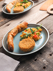 Tasty falafel with spicy bulgur and a vegetarian dough roll on a wooden table