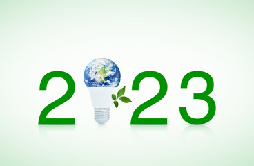 2023 text and earth globe inside led light bulb with fresh green tree leaves, Happy new year 2023...