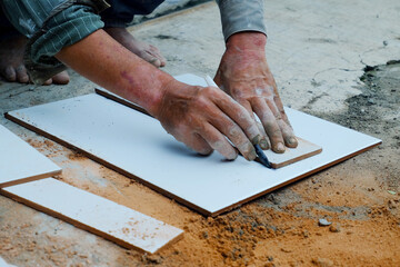 Artisan's hand is cutting ceramic with a grinder. Hand holding a ceramic tile cutting tool 