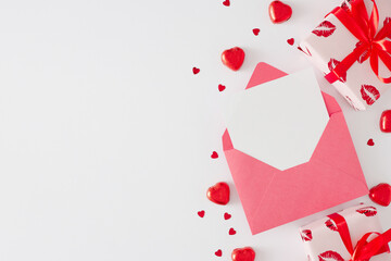 Valentines Day concept. Flat lay photo of gift boxes, envelope with letter and hearts sprinkles on white background with copy space. Minimal Valentines card idea.