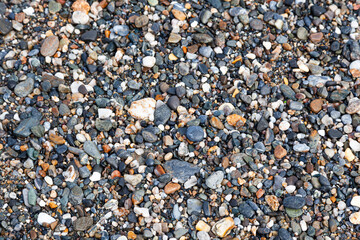 Background of sea stones. Stones of different shapes, sizes and colors on the seashore, close-up.
