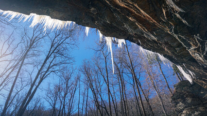 A scenic winter view of icicles hanging over Moore Cove Falls in Pisgah National Forest, North Carolina.