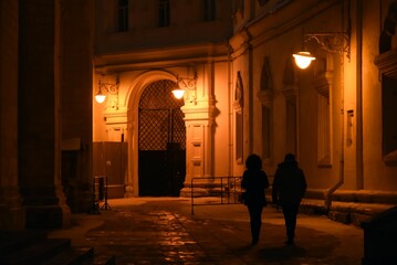 Moscow Kremlin at night. Woman and man walks by the ancient wall of a church.