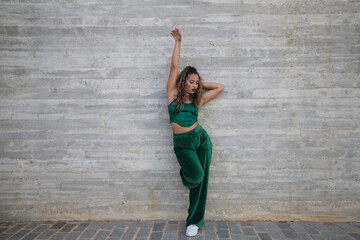 Latin woman, young and beautiful dancing modern dance on a background of gray cement in the street makes different expressions and postures. Concept dance, hip hop, dance, art, action, youth art.
