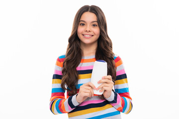 Naklejka premium Teenager child girl showing bottle shampoo conditioners or shower gel isolated on white background. Hair cosmetic product. Mock up bottle. Happy girl face, positive and smiling emotions.