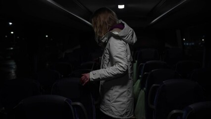 Close-up shot of woman searching for her seat in the night bus. Scared woman sits in the bus to get away from her angry boyfriend. Young blond hair woman running from home.
