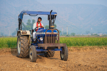 Indian farmer working with tractor at field.