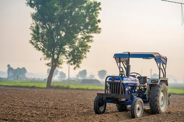 Schilderijen op glas New tractor standing at agriculture field. modern farming concept. © Niks Ads