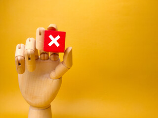 Wooden hand holding red cube with error sign.Concept of negative decision making or choice of vote...