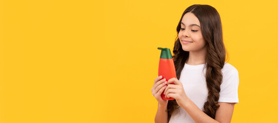 presenting cosmetic product for teen. kid with shower gel. happy girl hold shampoo bottle. Banner of child girl hair care, studio poster header with copy space.