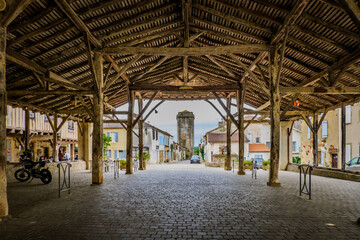 View on the main street and the medieval dungeon from the wooden covered market hall of Bassoues (South of France, Gers)