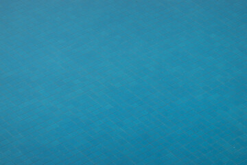 Background of swimming pool showing surface of water and tiles in the bottom