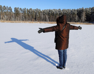 a woman and her shadow on a snow-covered frozen lake.