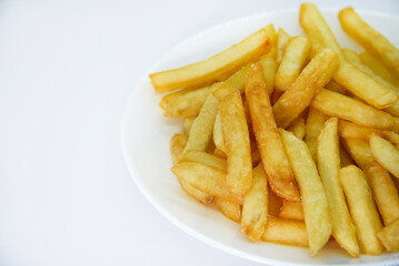 Yellow delicious French fries in white dishes. Fast food on a plate. Fried potatoes. Toasted potato slices on a white background.