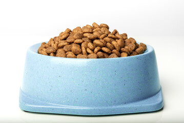 A full bowl of dry cat food on a white background.