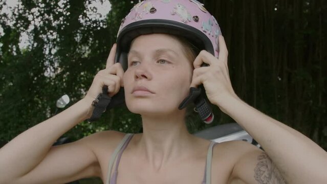 Woman putting on motorcycle helmet in slow motion.