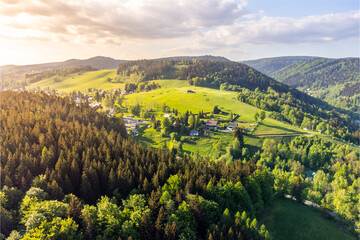 Albrechtice v Jizerskych horach town in the middle of green hills of Jizera mountains on sunny summer day. Czech Republic. Aerial view from drone.