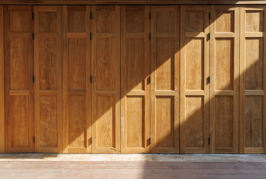 vintage old wooden thai bi folding facade. light and shadow on foldable timber door in thai style.