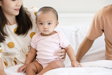 Toddlers are feeling safe and happy with their parents' care in bed at home. Asian family takes care of their children's health with love. Young children are learning to develop their brains.