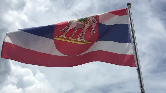 The Naval ensign of Thailand in the wind is the national flag with a red circle and white elephant on the red white and blue strip background.