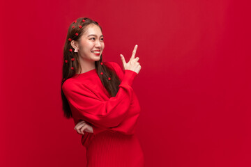 Young asian woman wearing red sweater dress with hand point to copy space on red background for...