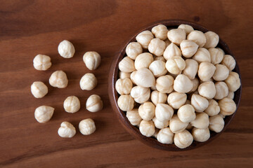 Fototapeta na wymiar Bowl full of hazelnuts on wooden background ,top view