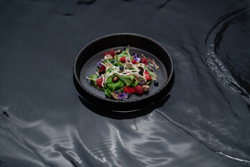 Ceramic bowl with black water with berry salad