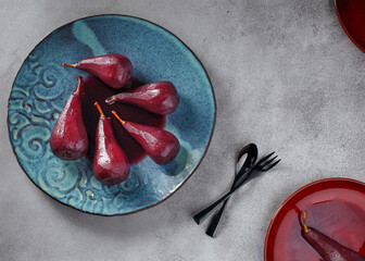 delicious red wine poached pears in spicy red wine syrup on the blue plate