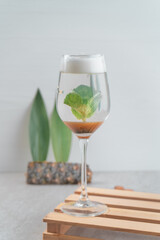 Specific alcoholic cocktail made in layers inside with a green leaf - especially for the menu