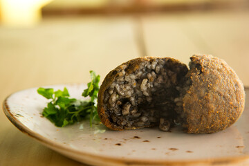 Cuttlefish black Arancini. Arancini are a specialty of Sicilian cuisine. They are stuffed breaded and fried rice balls or cones.