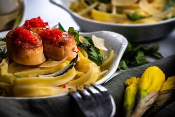 Pan-seared scallops and fettuccine with fresh basil leaves and shaved parmesan. Topped with lumpfish caviar.
