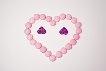 Sweets candies as heart with two glittering lilac hearts on white background. Valentines day...