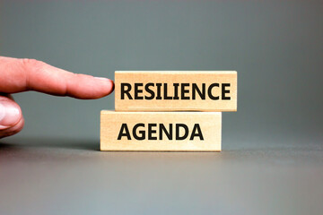 Resilience agenda symbol. Concept word Resilience agenda typed on wooden blocks. Beautiful grey table grey background. Businessman hand. Business and resilience agenda concept. Copy space.