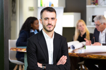 Formal business male portrait. Confident successful caucasian businessman with arms crossed, looks directly at camera