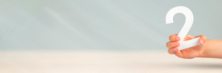 Number two in hand. Hand holding white number 2 on blurred background with copy space. Concept with number two. 2 percent, birthday 2 years old, couple, two, double