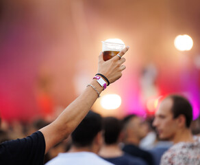unrecognizable person holding a glass of beer at a music festival