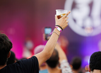 unrecognizable person holding a glass of beer at a concert