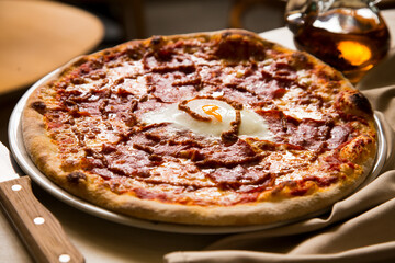 Pizza with egg in the middle. Neapolitan pizza with tomato sauce, cheese and ham. Authentic Italian recipe.