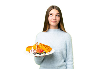 Teenager girl holding waffles over isolated chroma key background and looking up