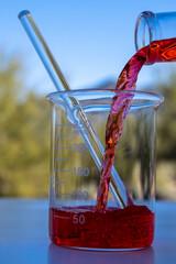 Pouring red liquid in a glass container outside