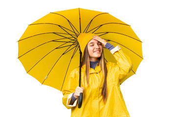 Teenager girl with rainproof coat and umbrella over isolated chroma key background smiling a lot