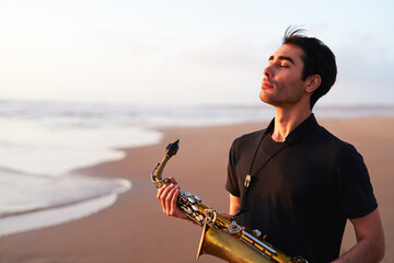 portrait young latino male model musician holds a saxophone in his hands and eyes closed enjoying...