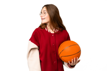 Teenager girl playing basketball over isolated chroma key background laughing in lateral position